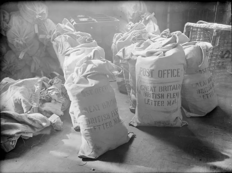 Full canvas mail sacks stamped Post Office and Letter Mail stand in rows on a sorting office floor.